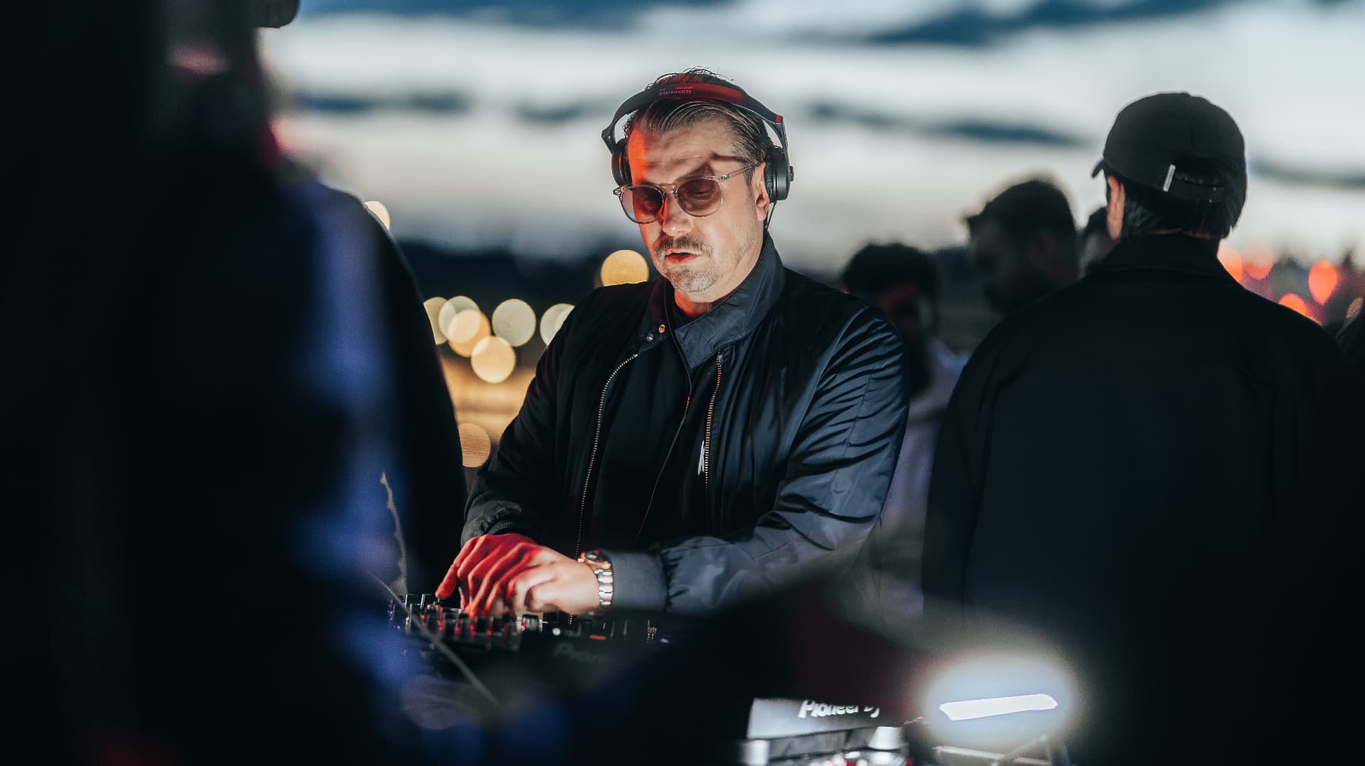DJ with headphones behind the decks at an open air set, event photography by Paul Rumplmaier